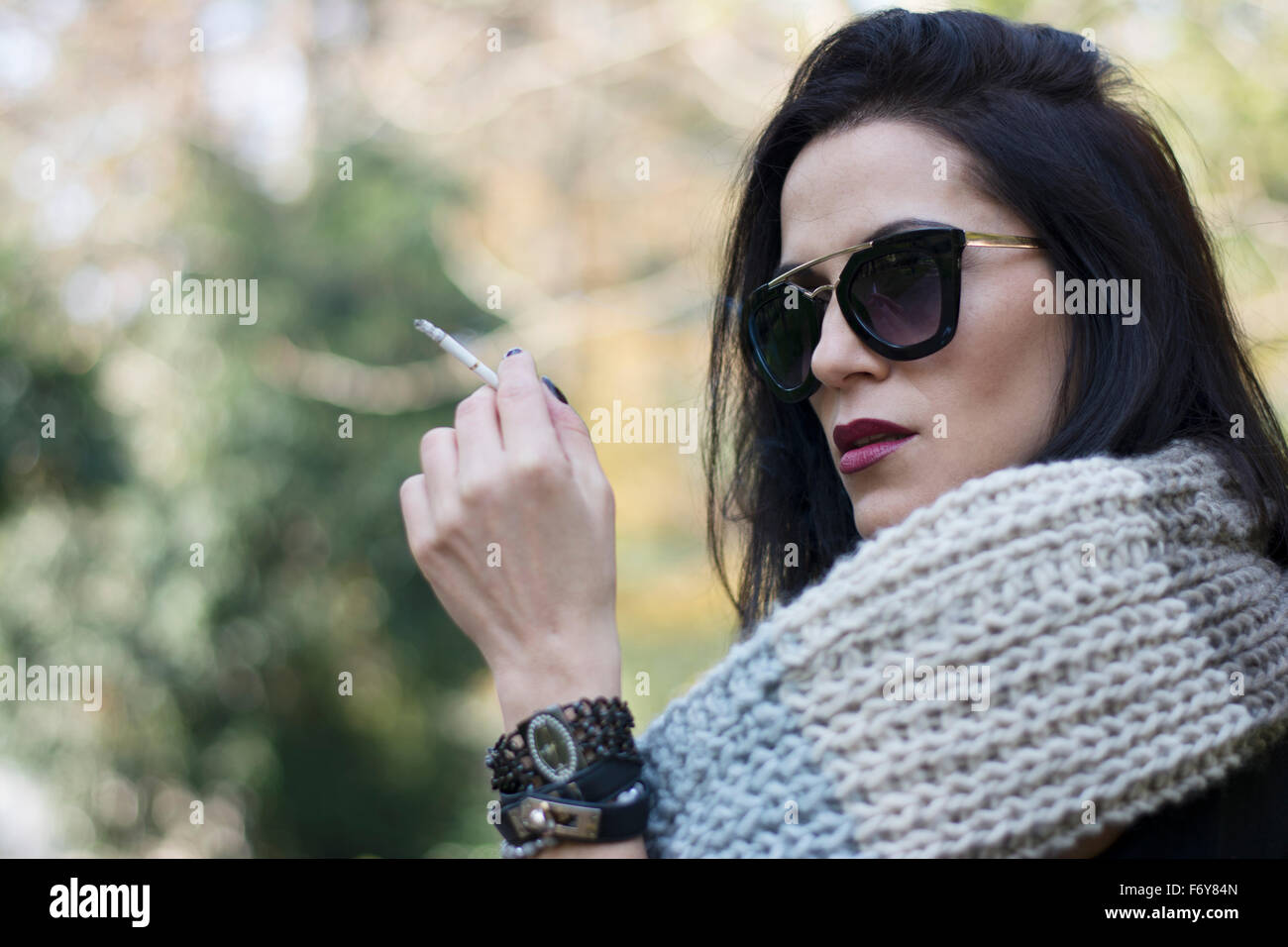 Attraente capelli neri donna godendo il fumo di sigarette in park Foto Stock