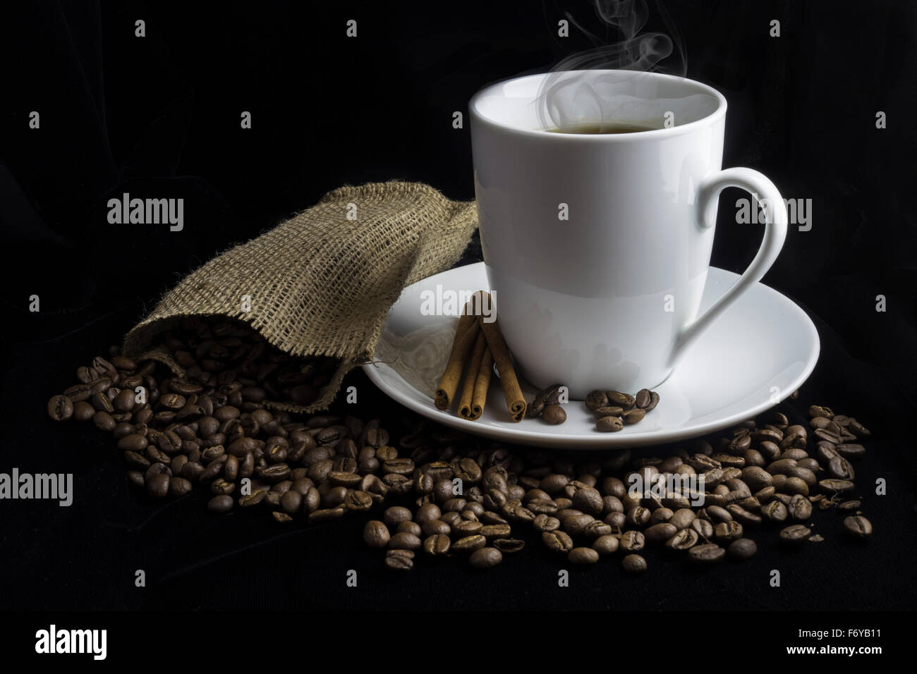 Tazza di caffè con i chicchi di caffè nei dintorni di piattino con borsa di tela. Foto Stock