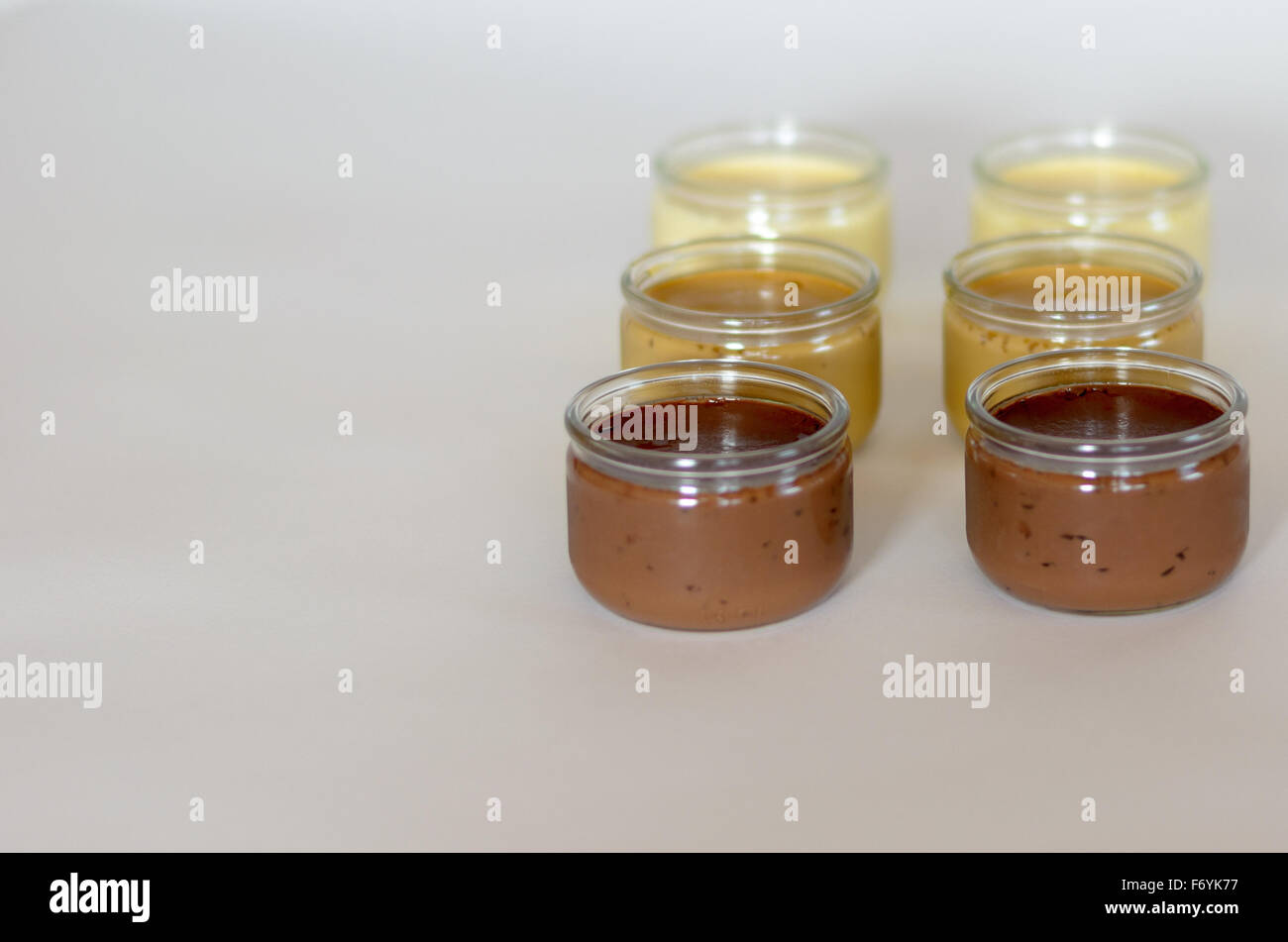 6 bicchieri di pudding in una fila, sfondo bianco Foto Stock
