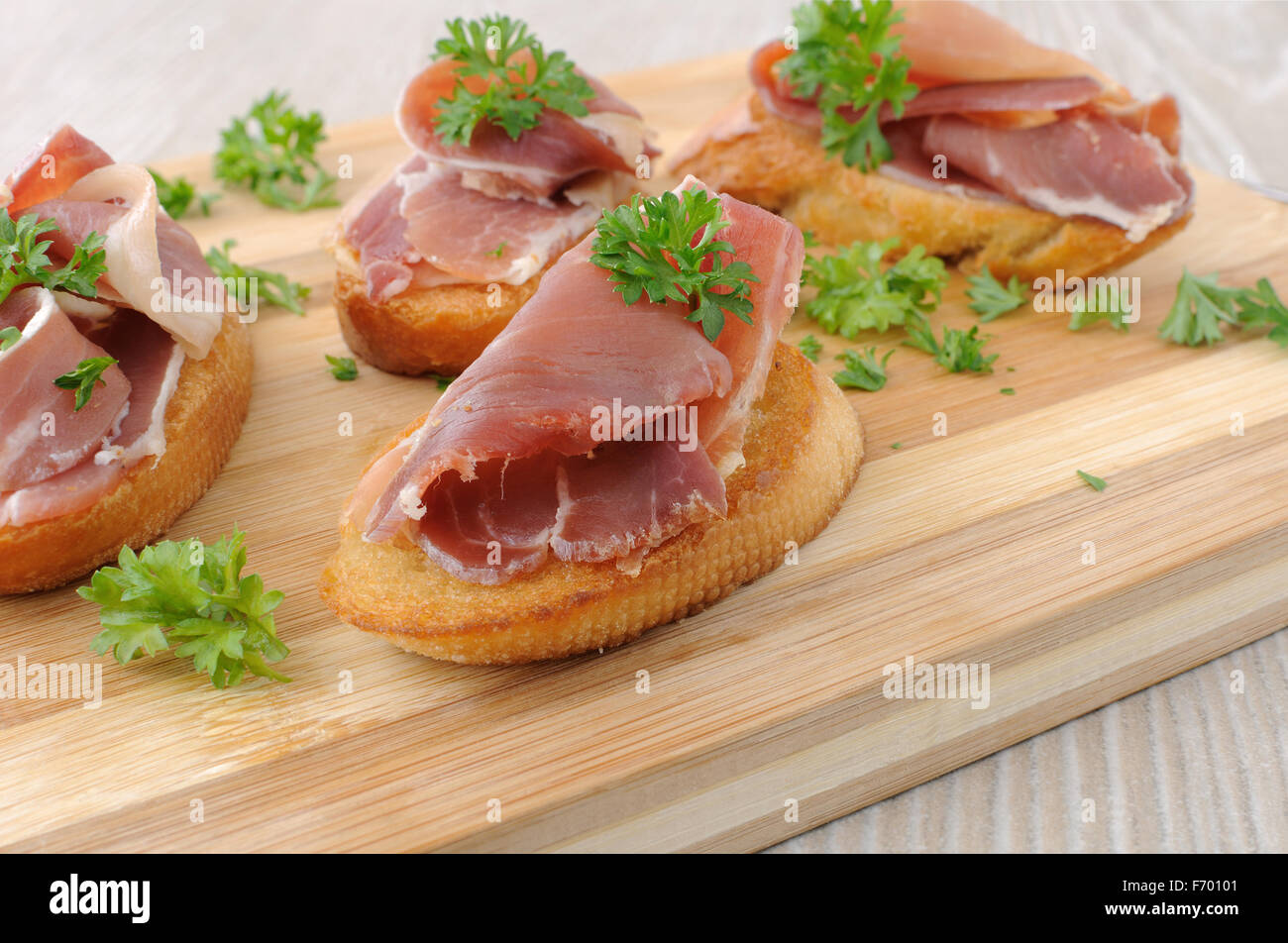 Fette di pane con lo spagnolo jamon serrano su una tavola di legno Foto Stock