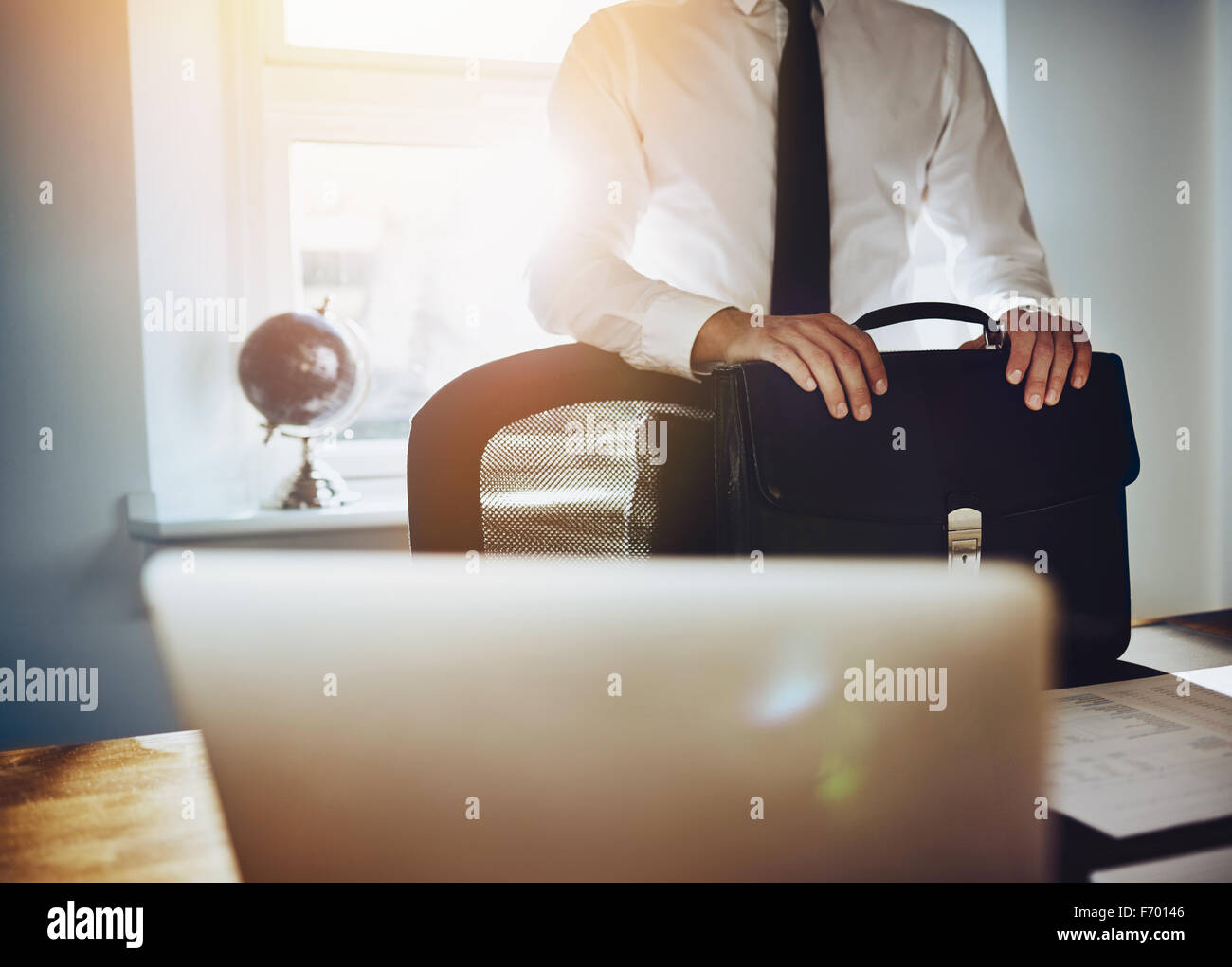 Il concetto di business, uomo in piedi alla scrivania con valigetta portatile e indossando un classico abito di business Foto Stock