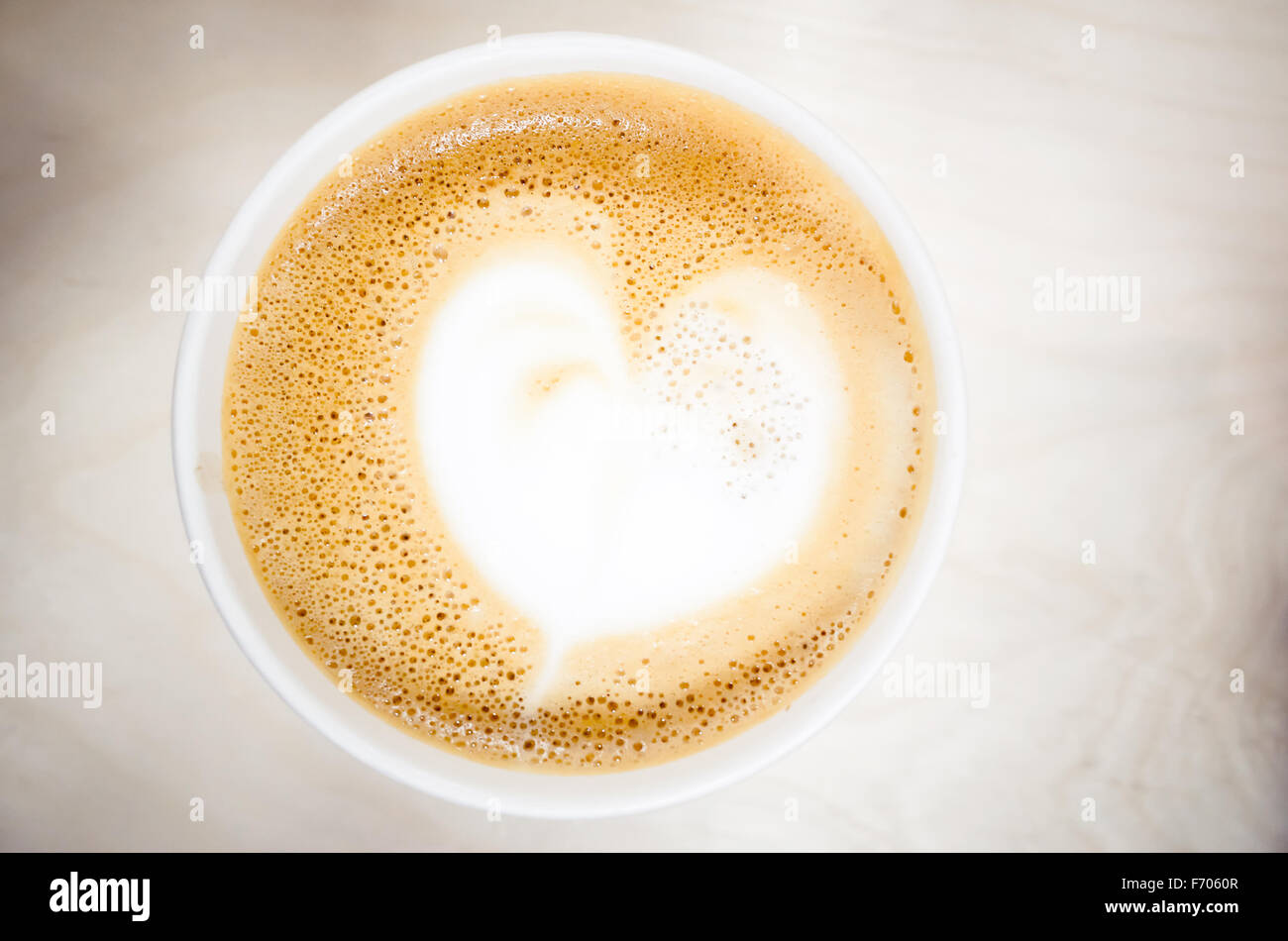 Tazza di cappuccino con caffè e a forma di cuore in schiuma di latte. Vista dall'alto, il fuoco selettivo Foto Stock