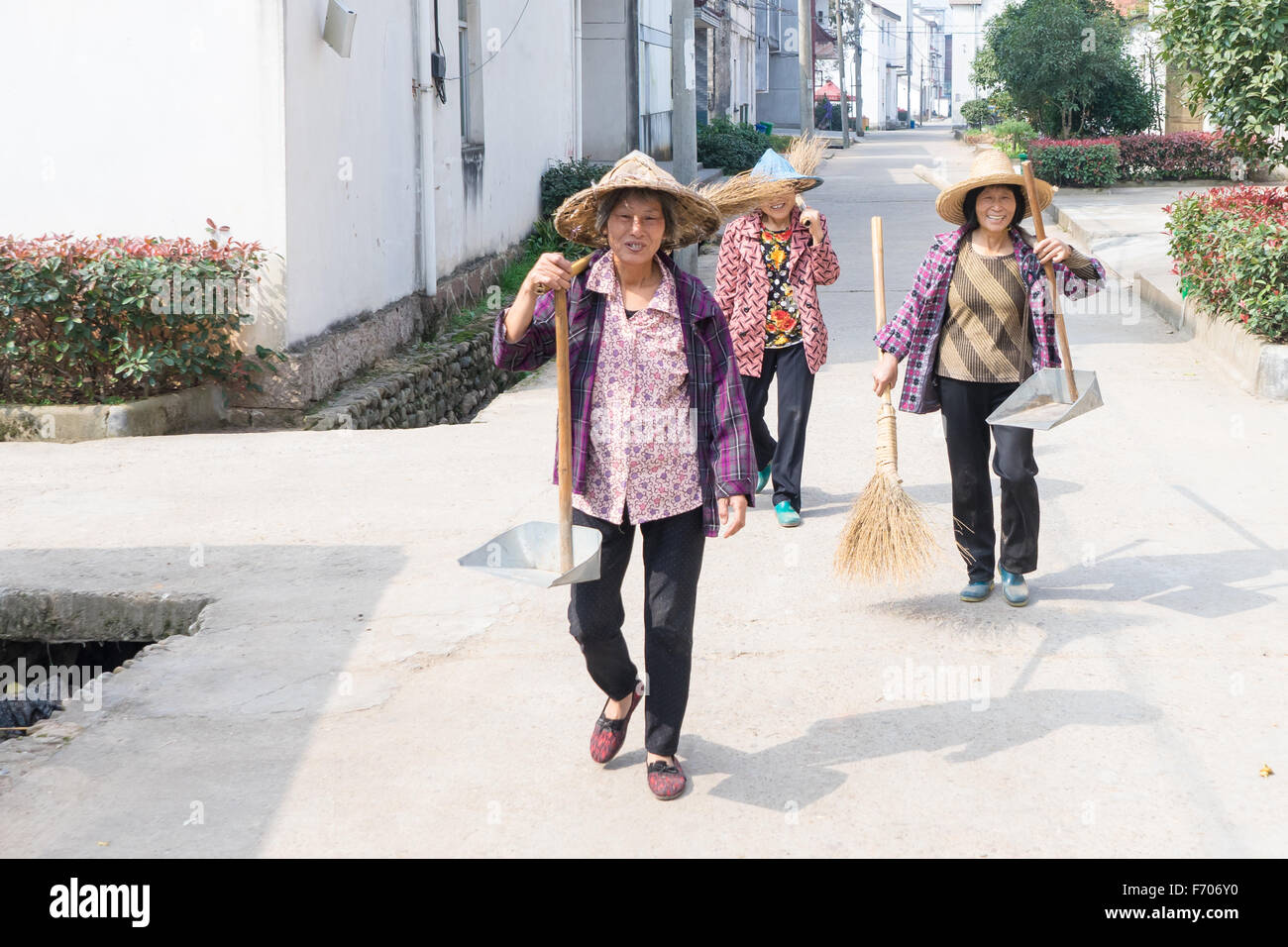 Tre mogli di casa a piedi giù per la strada nel villaggio lamellatura, Jinhua, Cina Foto Stock