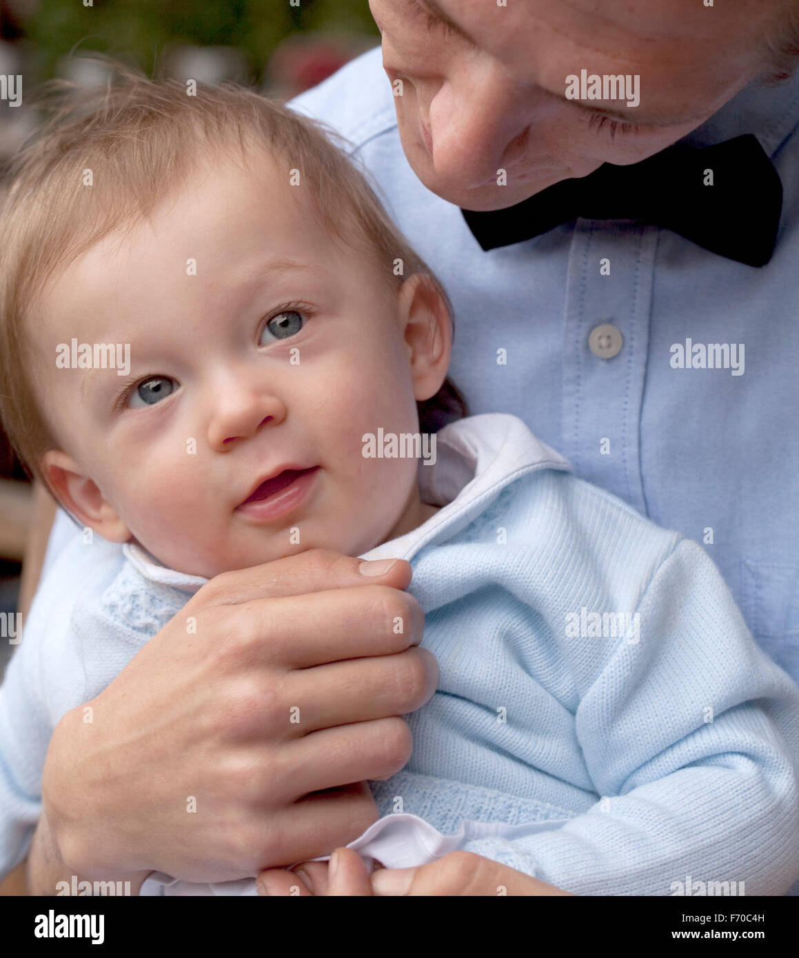 Molto amato bambino. Un giovane bambino viene tenuto delicatamente dal suo padre mentre lui guarda giù con tanto amore nella sua espressione. Foto Stock