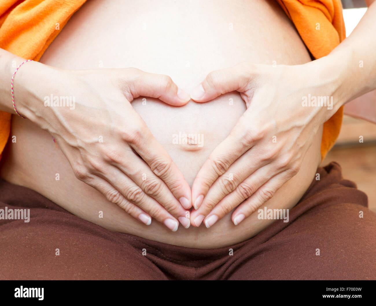 Maternità maternità concetto.Donna Incinta tenendo le sue mani a forma di cuore sul suo bambino bump. Pancia in gravidanza con le dita Foto Stock