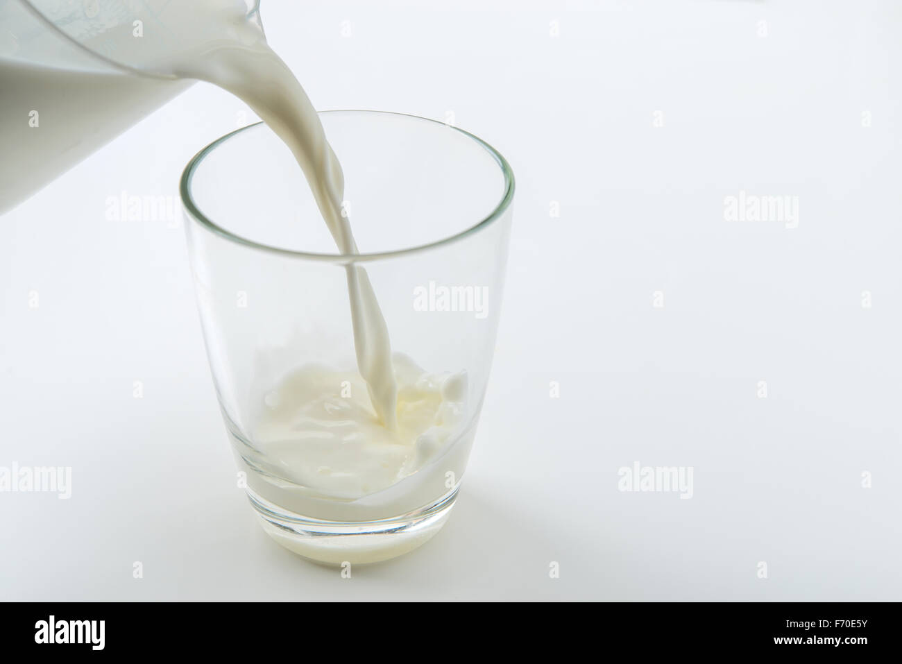 Il latte che viene versato in un bicchiere Foto Stock