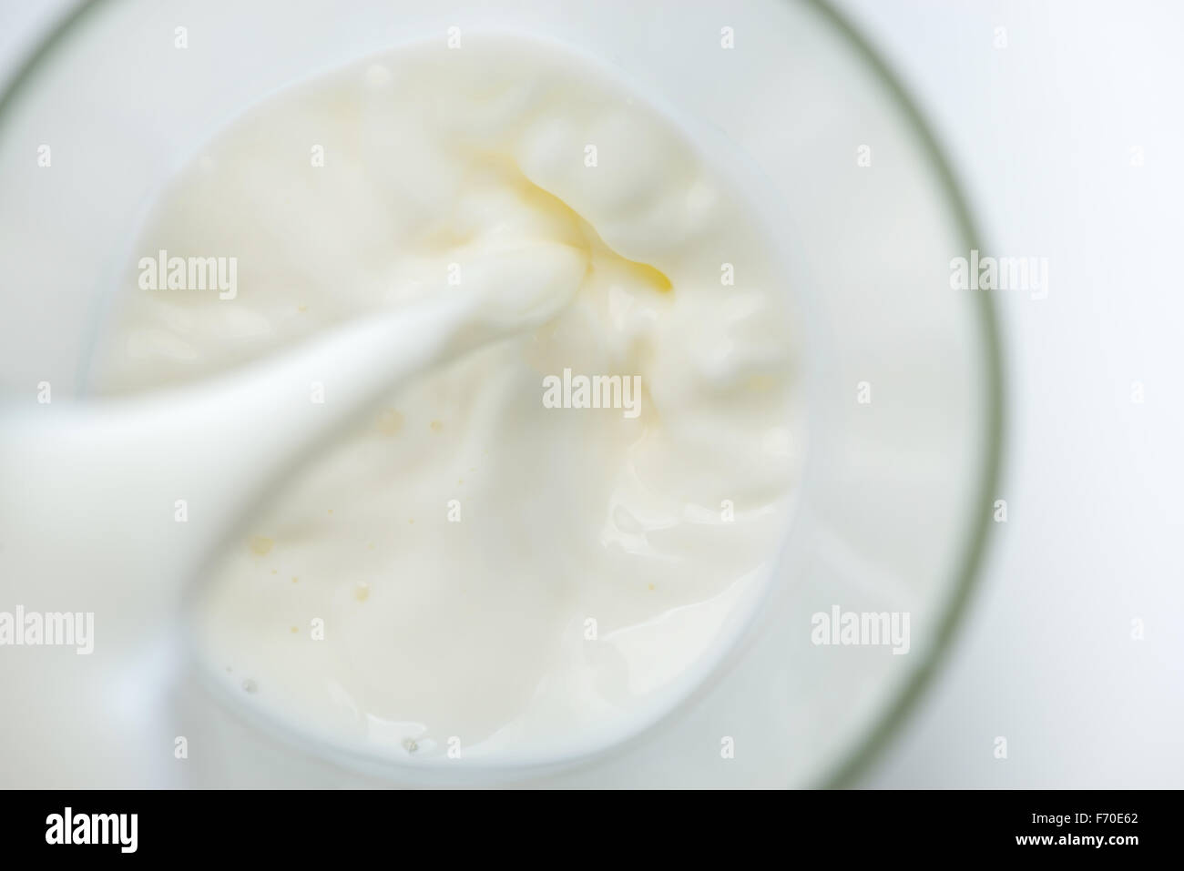Il latte che viene versato in un bicchiere Foto Stock