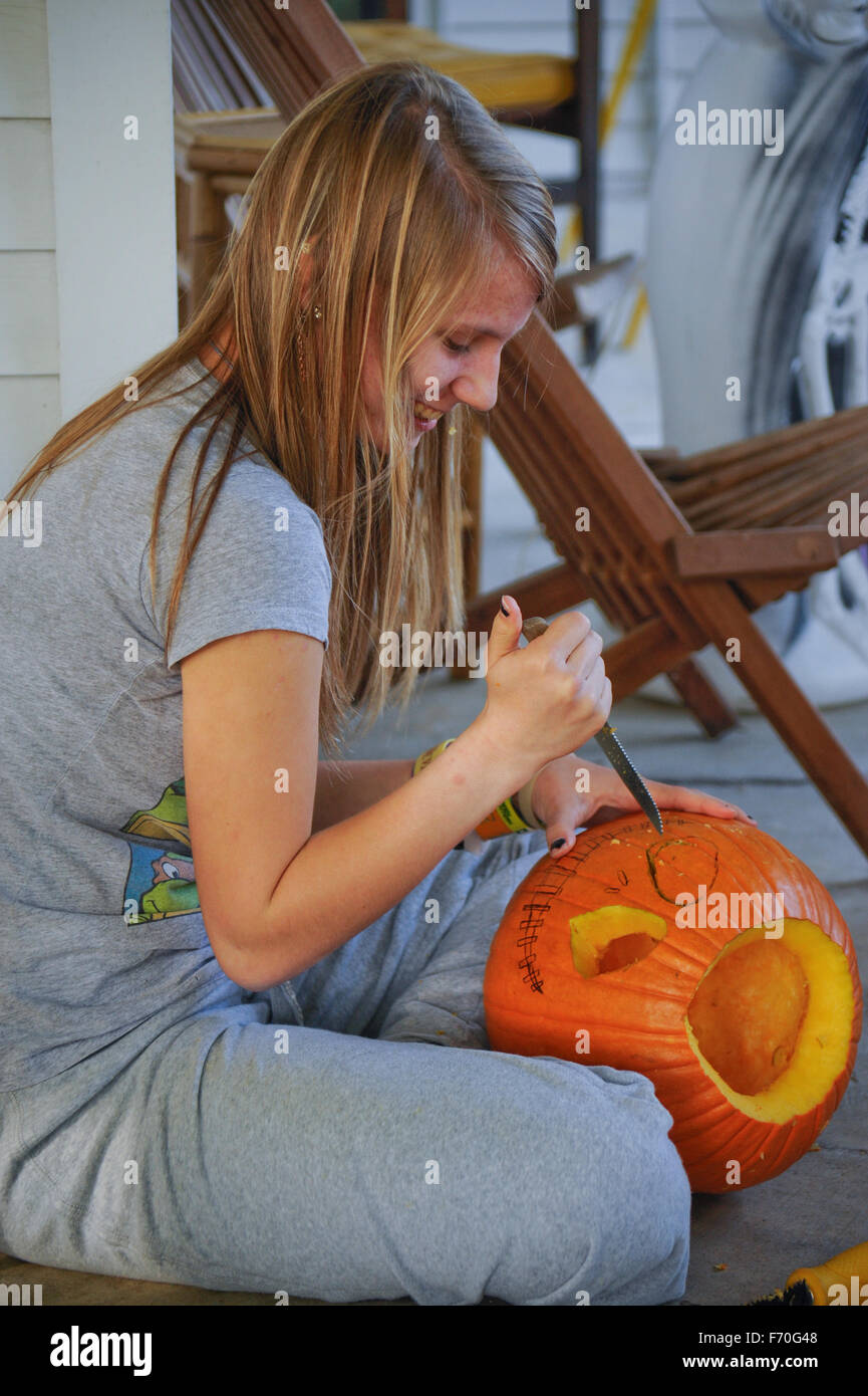 Teen ragazza bionda tagliare la zucca di Halloween Foto Stock