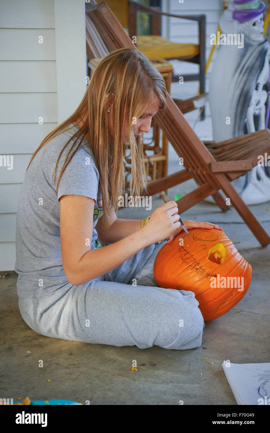Teen ragazza bionda tagliare la zucca di Halloween Foto Stock