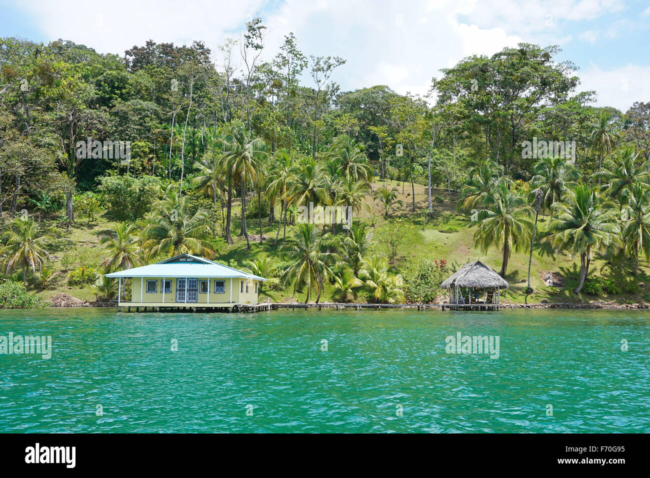 Albergo sul fronte oceano in America centrale con palme di cocco e una casa con capanna su acqua, Costa Caraibica di Panama, Bocas Foto Stock