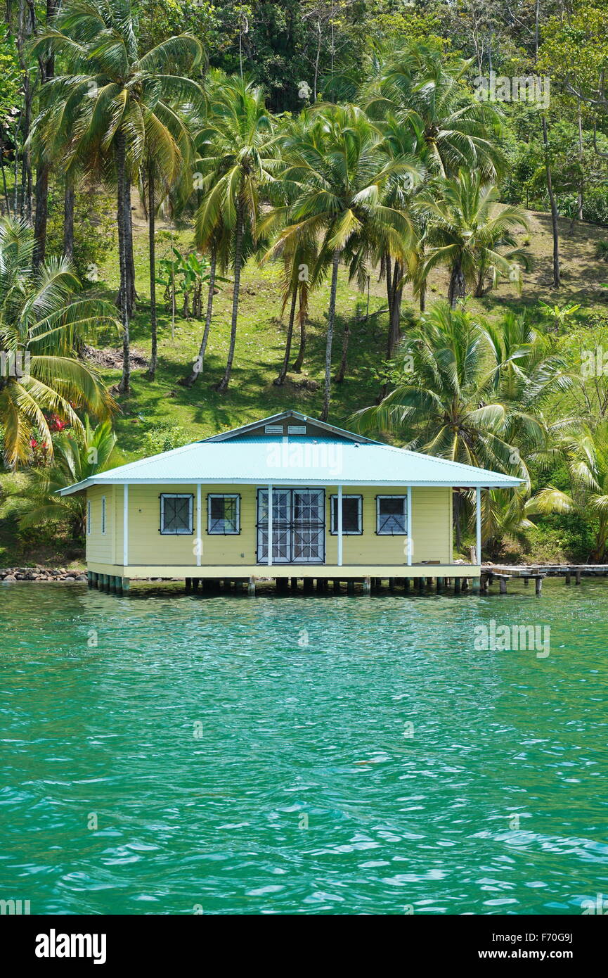 Tropical home su palafitte sopra il mare con palme da cocco sulla terra, Costa Caraibica di Panama, Bocas del Toro, America Centrale Foto Stock