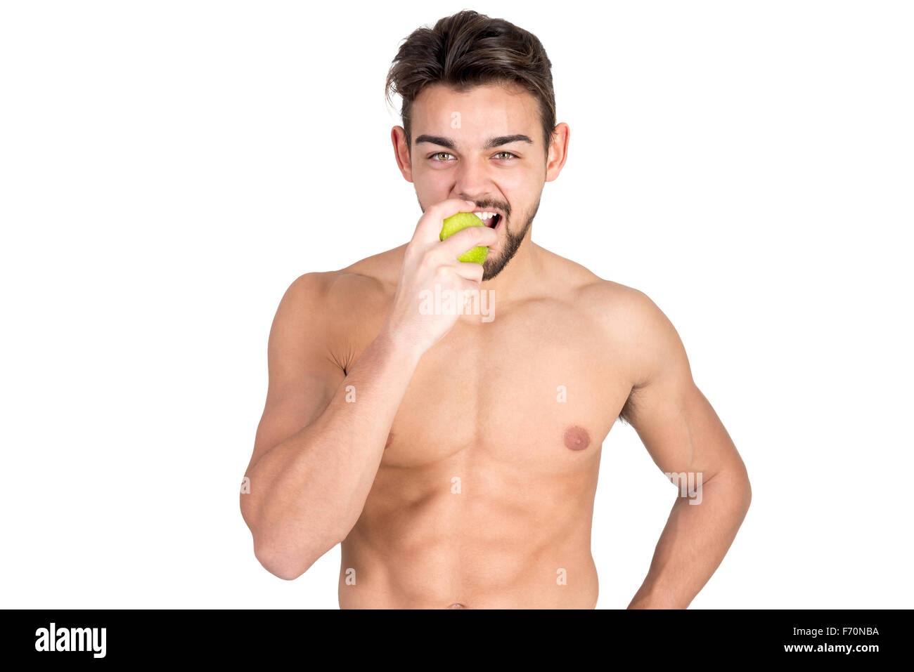 Bello e montare il giovane uomo mangiare un apple isolato in bianco Foto Stock