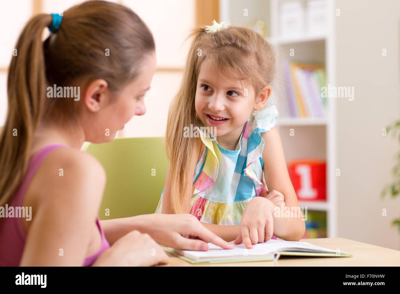 Madre o un insegnante donna aiutare bambino con compiti Foto Stock