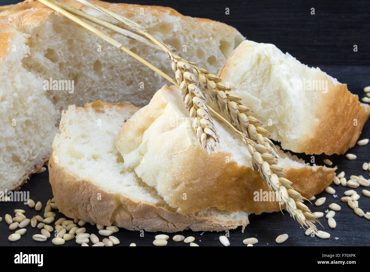 Di grano a fette di pane bianco con grani di grano su sfondo nero Foto Stock