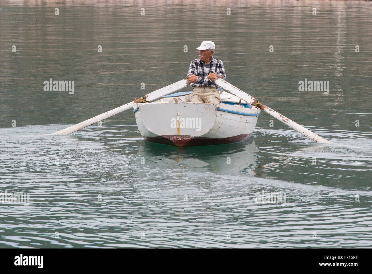 Pescatore greco il canottaggio la sua barca fuori del porto di Ermioni, in Grecia e nel Mare Egeo Foto Stock
