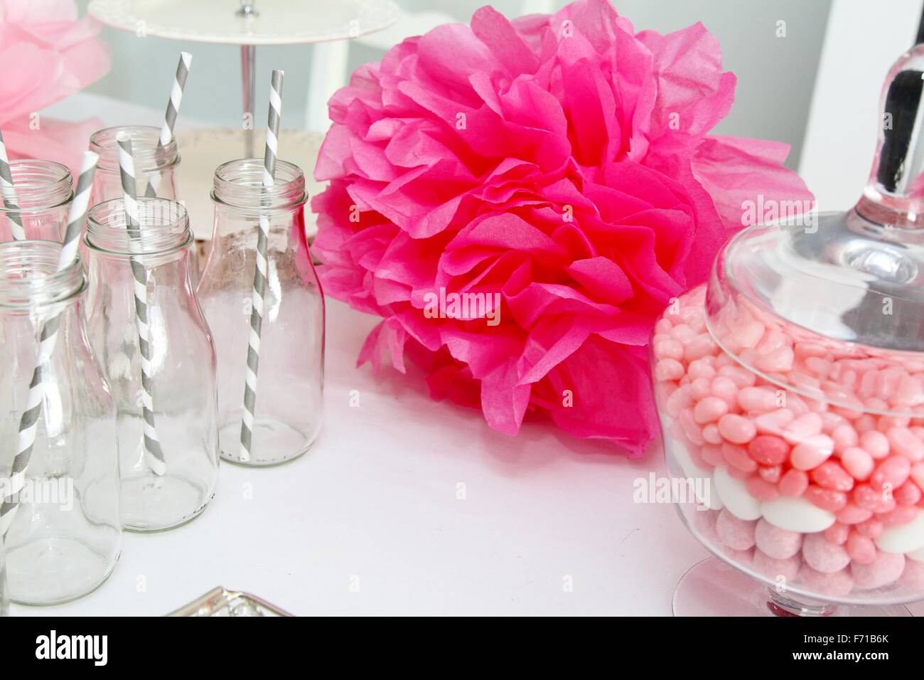 Celebrazione con pompon rosa, Jelly Beans e bottiglie con cannucce grigio Foto Stock