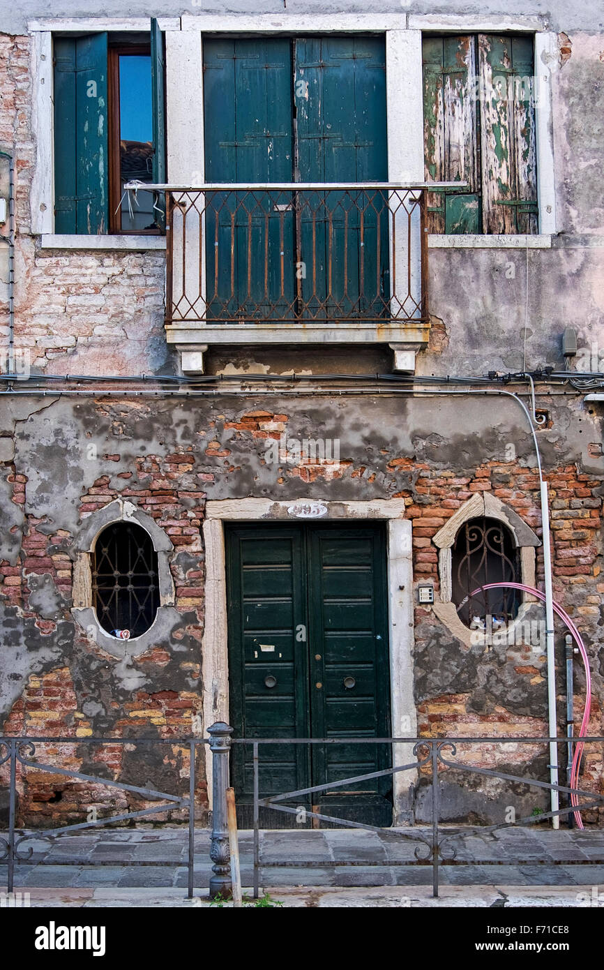 Venezia Italia - casa diroccata esterno con acqua danneggiato, weathered muro di mattoni, finestre con persiane di pelatura Foto Stock