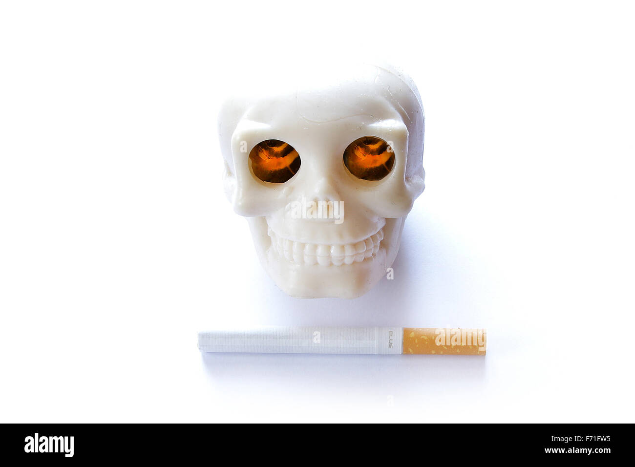 Il fumo uccide vintage teschio umano con bruciare gli occhi illuminati e sigaretta su sfondo bianco Foto Stock