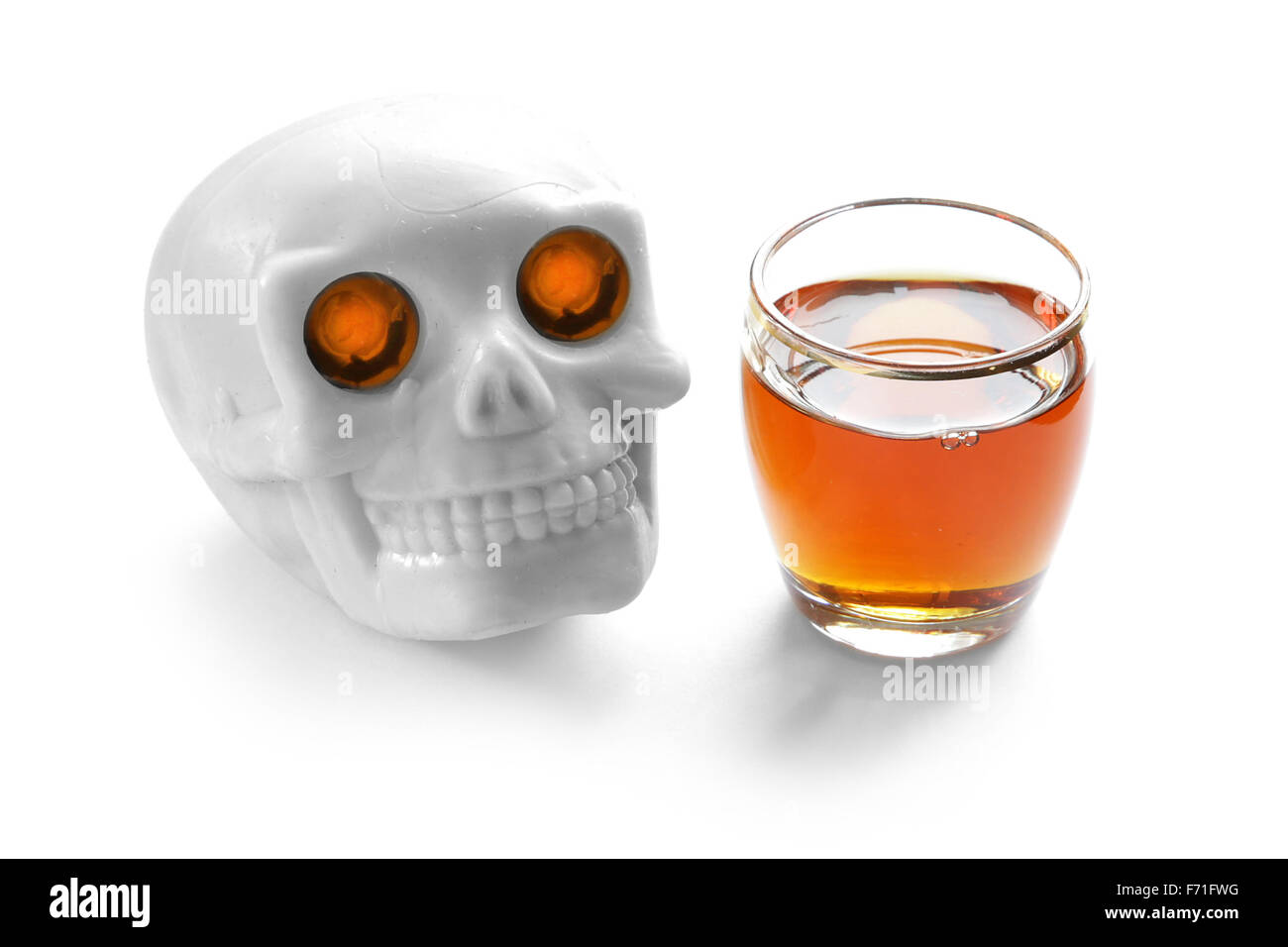 L'alcool uccide vintage teschio umano con ardente illumina gli occhi e whiskey shot su sfondo bianco Foto Stock