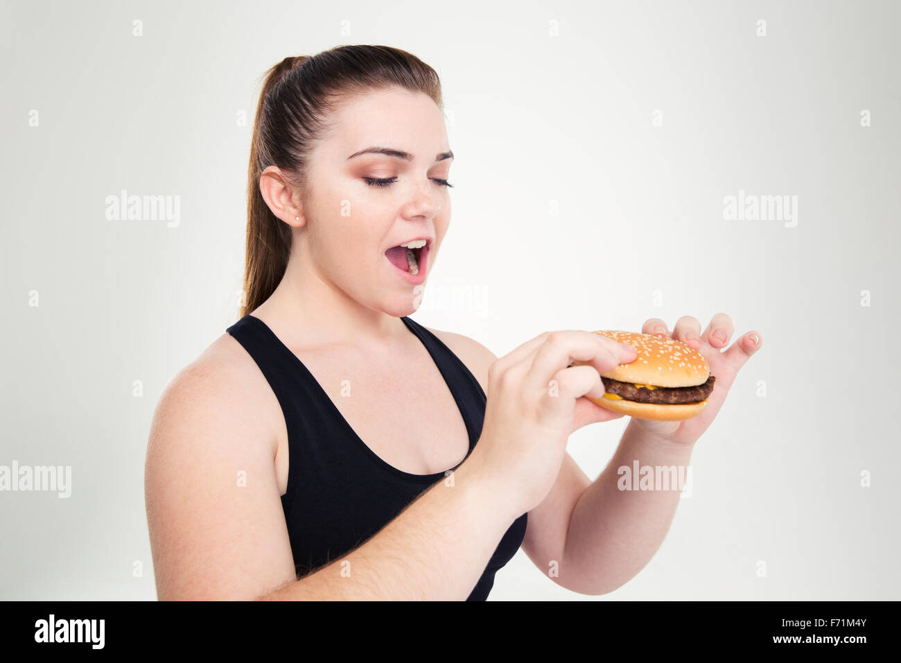 Ritratto di una donna grassa mangiare hamburger isolato su uno sfondo bianco Foto Stock