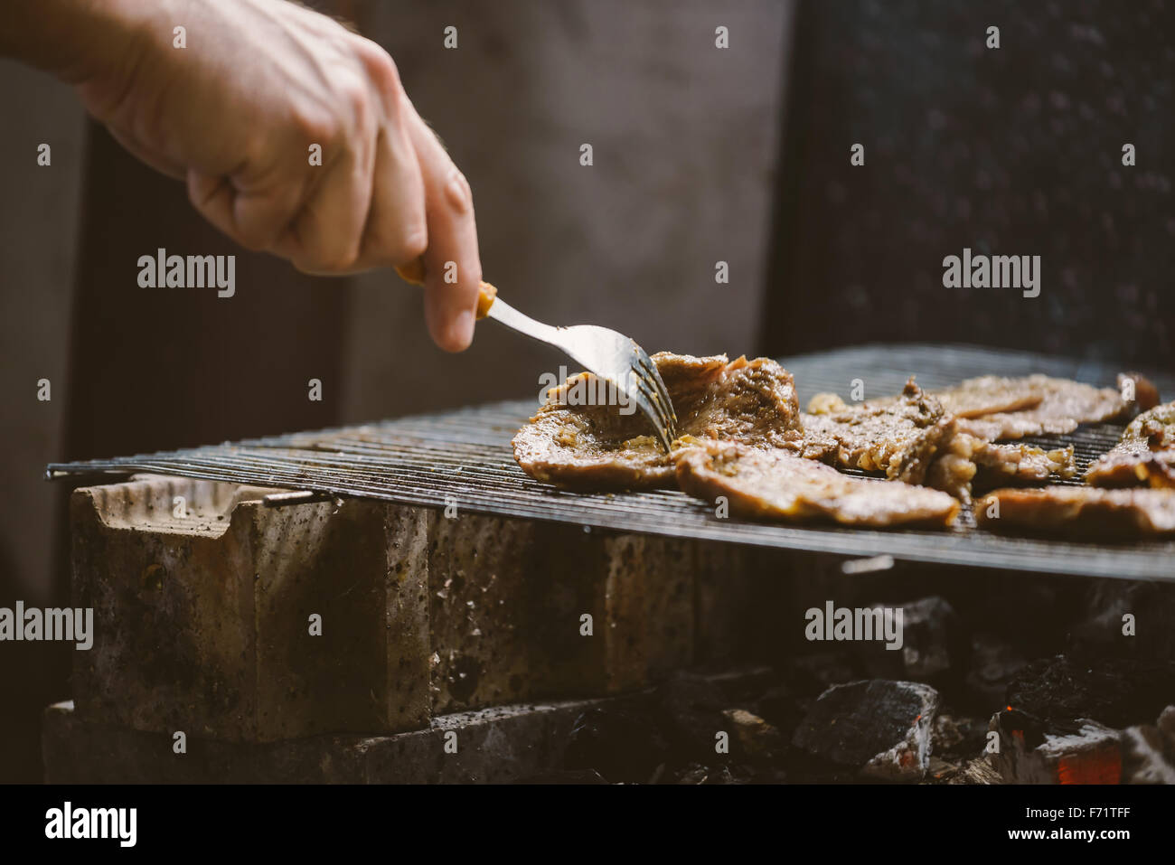 Mangiare malsano, l uomo per grigliare carne di maiale braciole sul barbecue, luce naturale, dai toni retrò, il fuoco selettivo Foto Stock