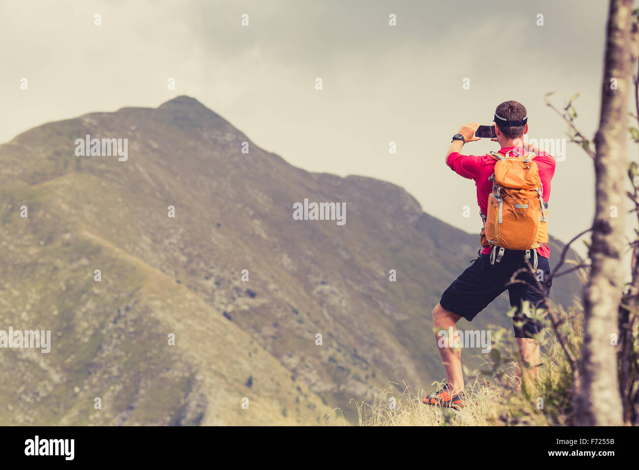 Escursionismo uomo, backpacker, scalatore o trail runner in montagne guardando il bellissimo paesaggio ispiratore vista. Scattare una foto, Foto Stock