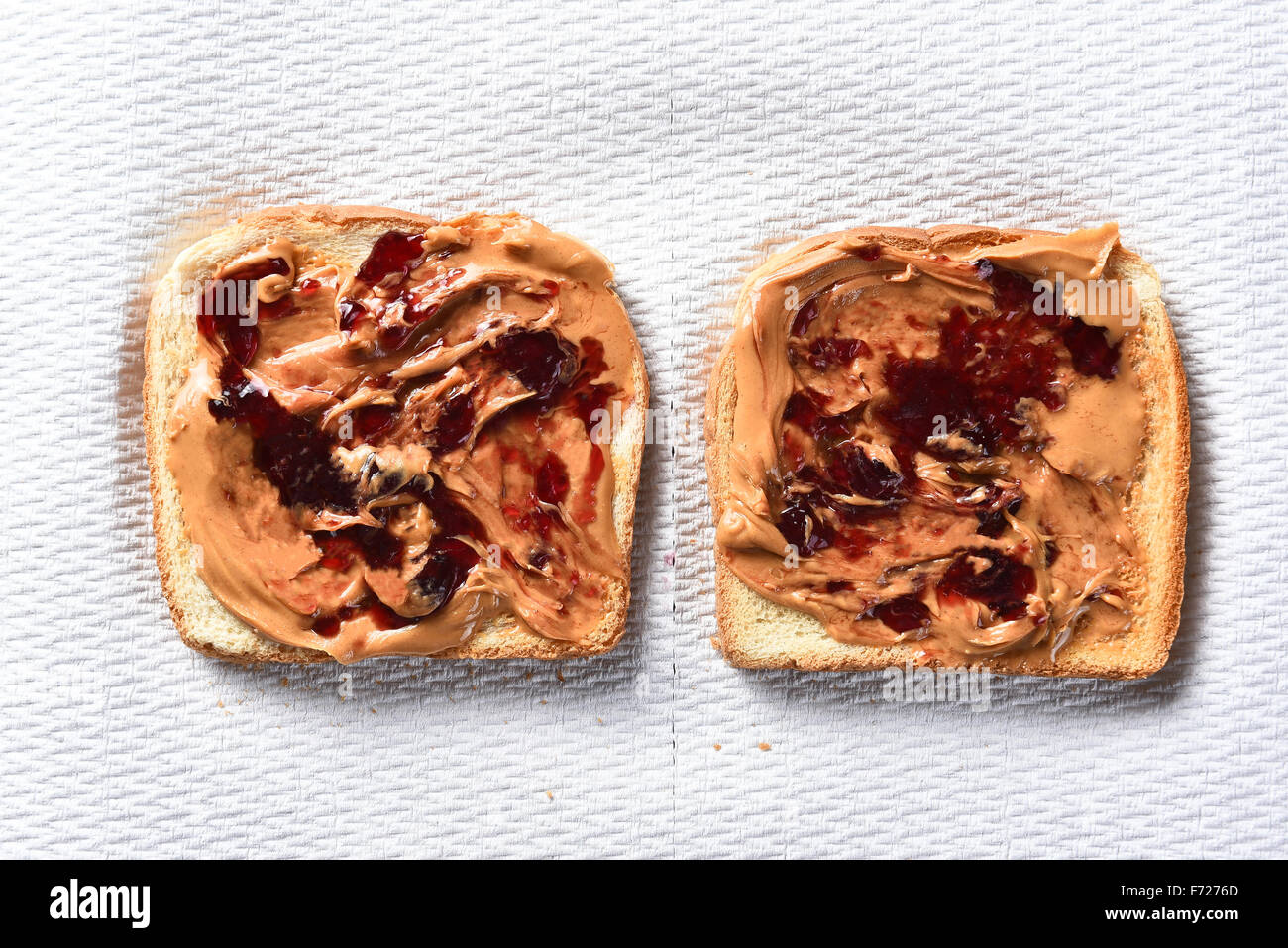 Vista aerea di due fette di pane tostato con burro di arachidi e gelatina di uva. Formato orizzontale su un tovagliolo di carta. Foto Stock