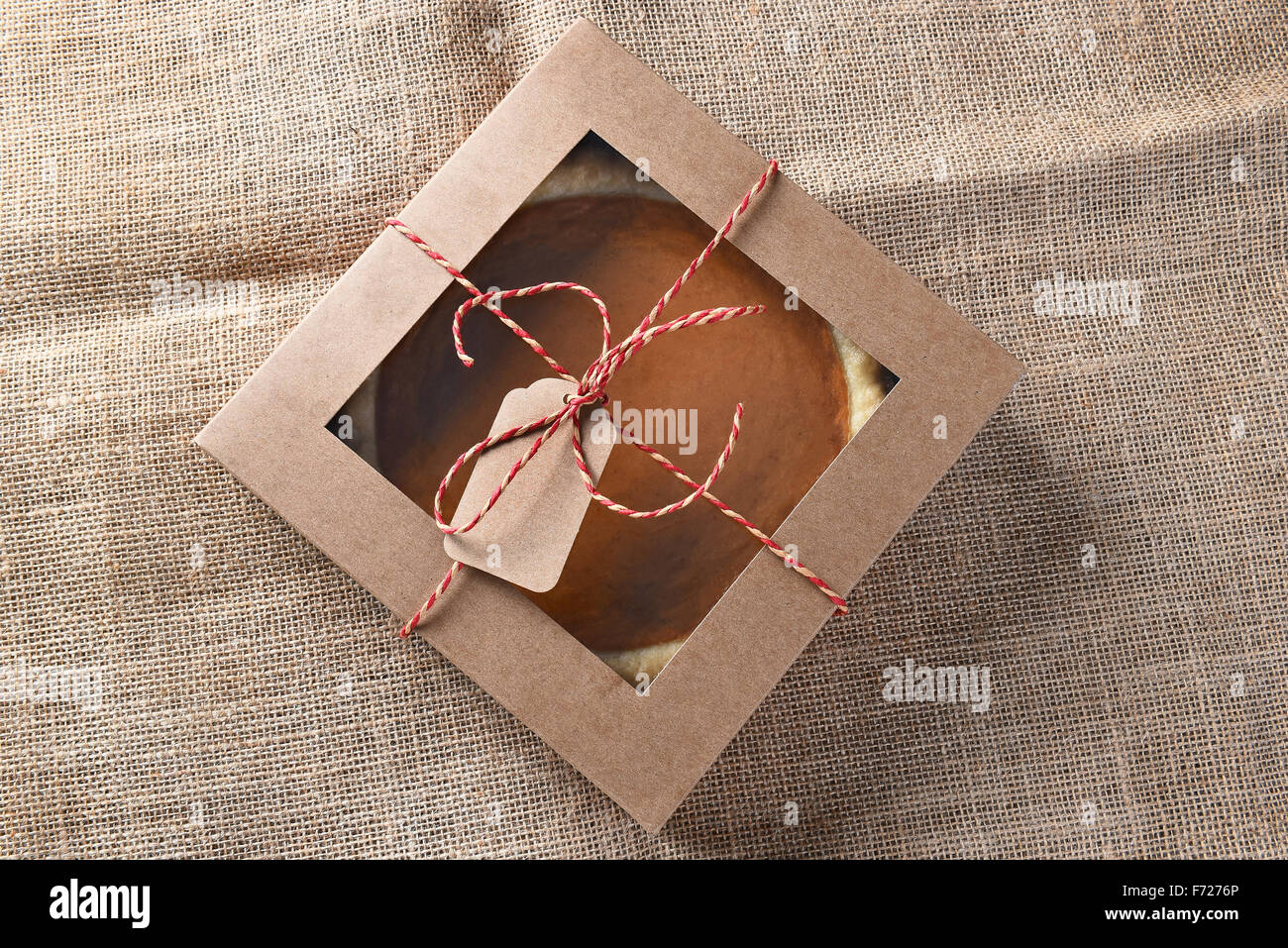 Fresca torta di zucca in una scatola da forno legati con spago e un tag vuoto. Elevato angolo di visione su una tela ruvida la superficie. Foto Stock