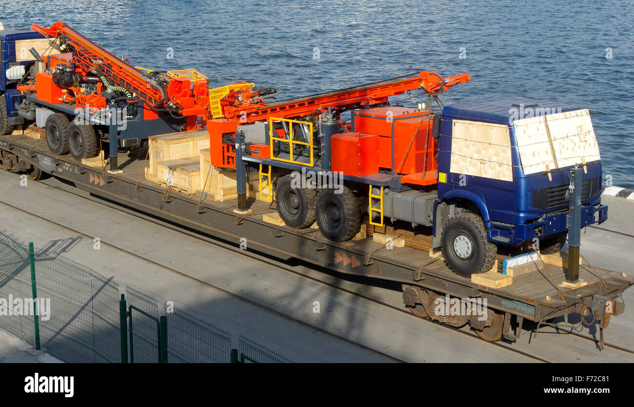 Trasporto di veicoli speciali su piattaforme ferroviarie, veicoli sovraccarichi sulla piattaforma della nave in porto Foto Stock