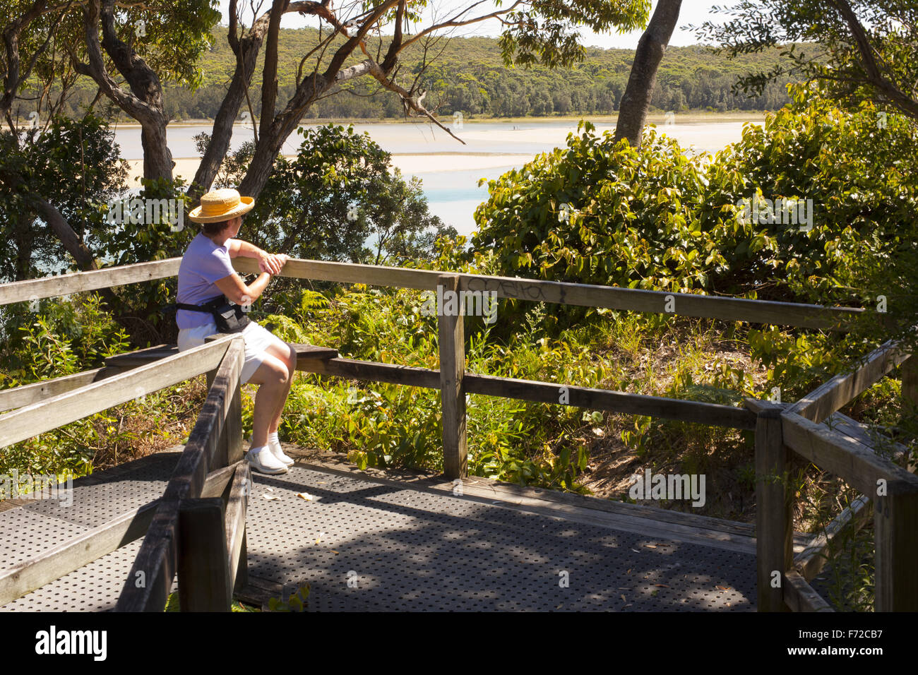 Donna seduta su un banco e affacciato sul lago Conjola ingresso Foto Stock