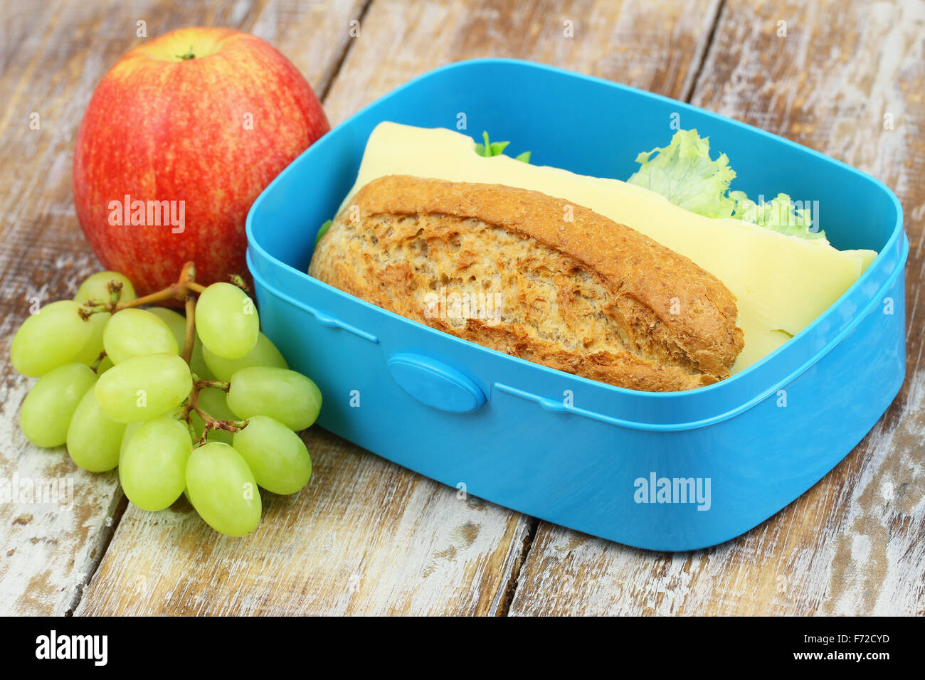 Scuola scatola di pranzo costituito da marrone a sandwich di pane con formaggio, apple e uva Foto Stock