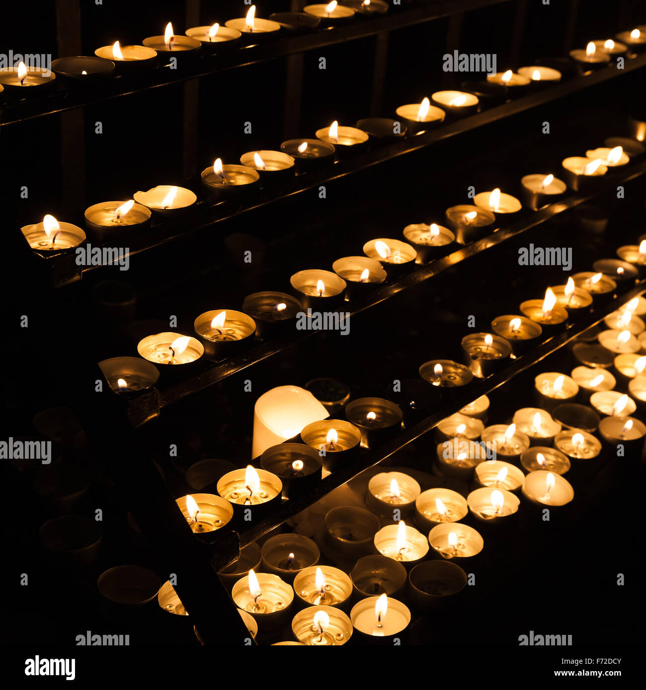 Piccole candele accese sugli scaffali in dark chiesa cattolica Foto Stock