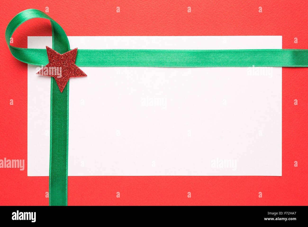 Bianco Natale carta o un invito con nastro verde su sfondo rosso Foto Stock