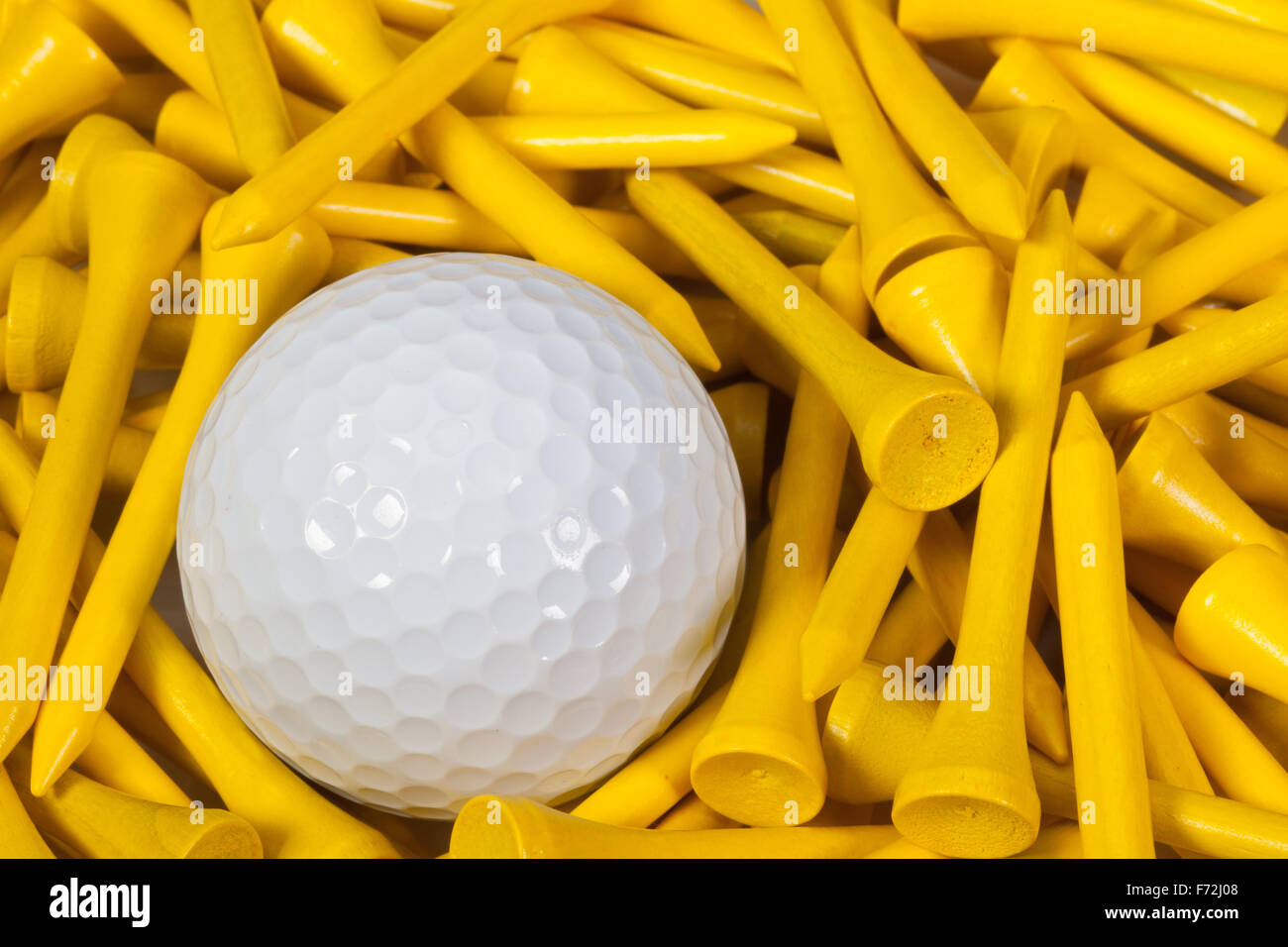 White pallina da golf che giace tra legno giallo golf tees Foto Stock