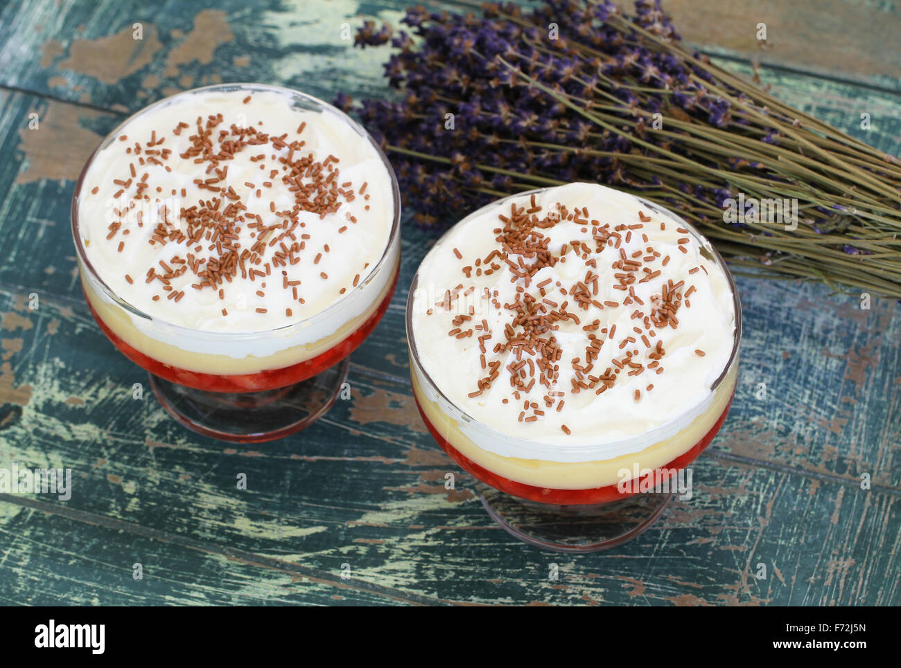 Due zuppa di fragole dolci con panna montata e spolverate con il cioccolato rustico superficie in legno Foto Stock