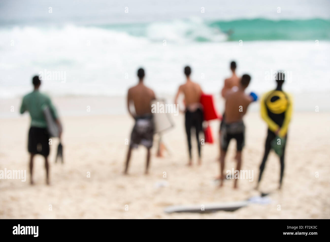 Gruppo di surfisti brasiliani in piedi con tavole boogie guardando le onde in arrivo a Arpoador a Rio de Janeiro in Brasile Foto Stock