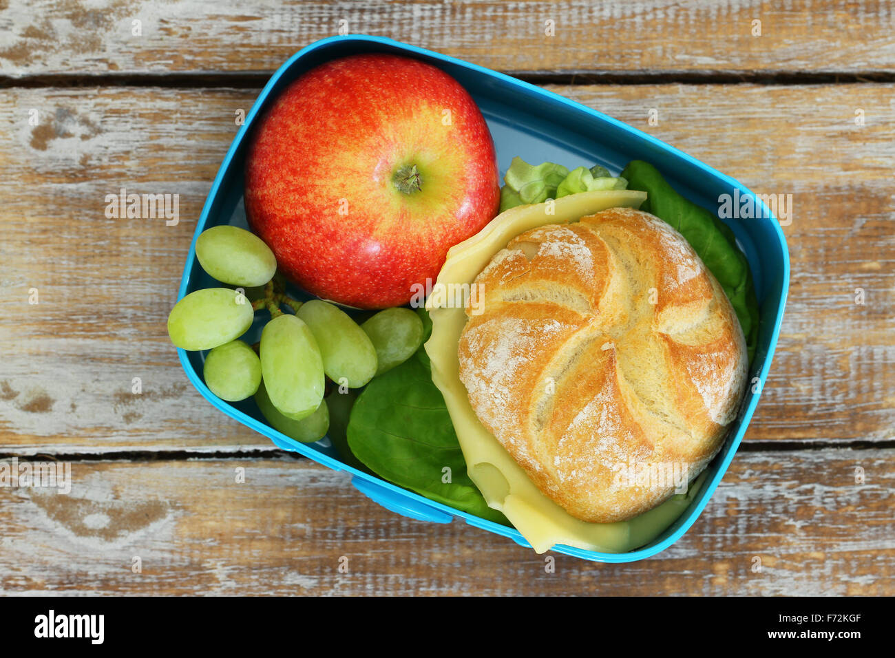 Scuola scatola di pranzo con sandwich di formaggio, Rosso mela e uva Foto Stock