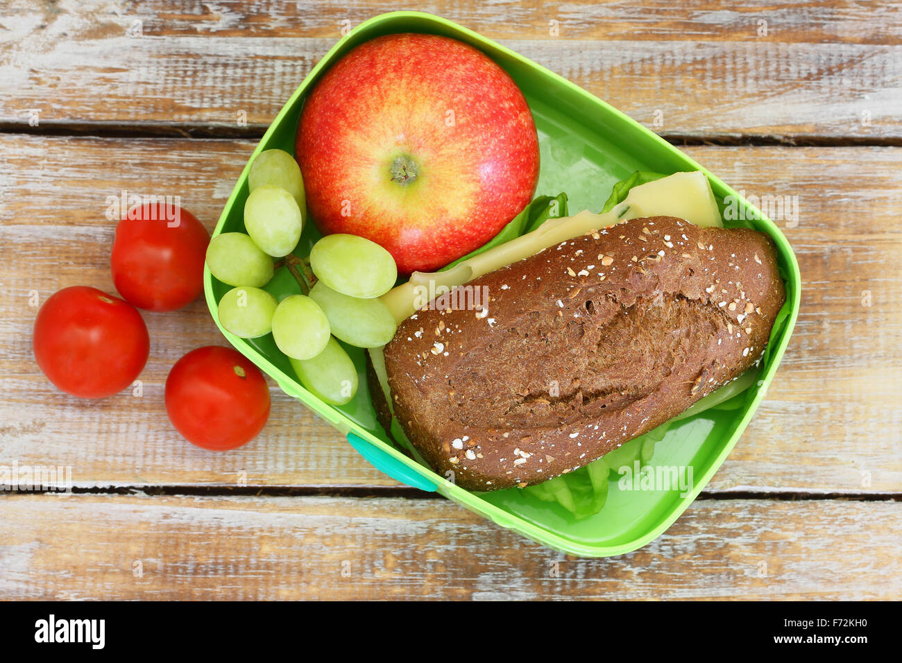 Scuola di sano scatola di pranzo con pane marrone sandwich di formaggio, rosso apple, uva e pomodorini Foto Stock