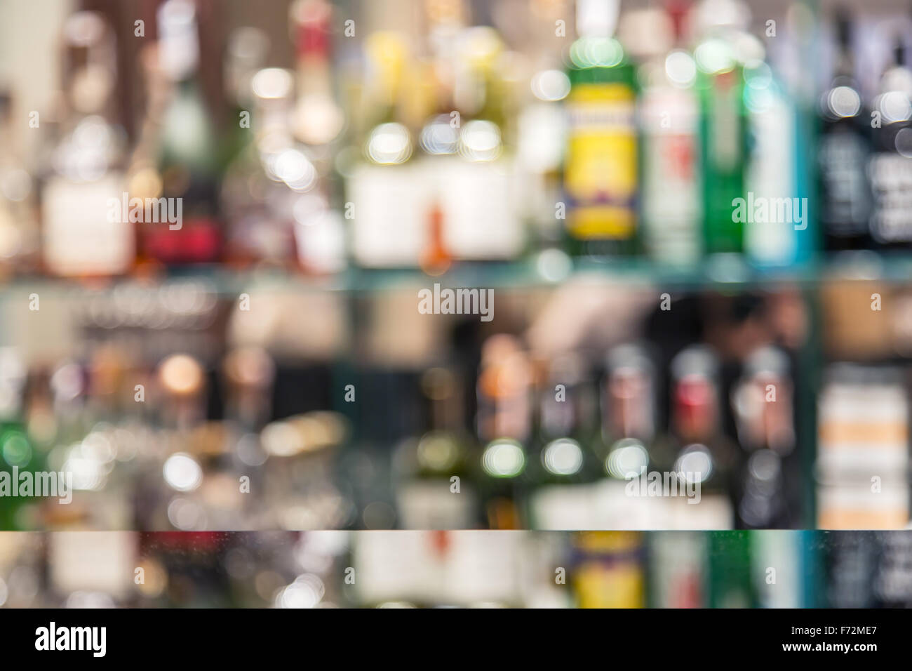 Barra di vetro contatore con ripiani sfocate con bottiglie di alcol sullo sfondo. Foto Stock