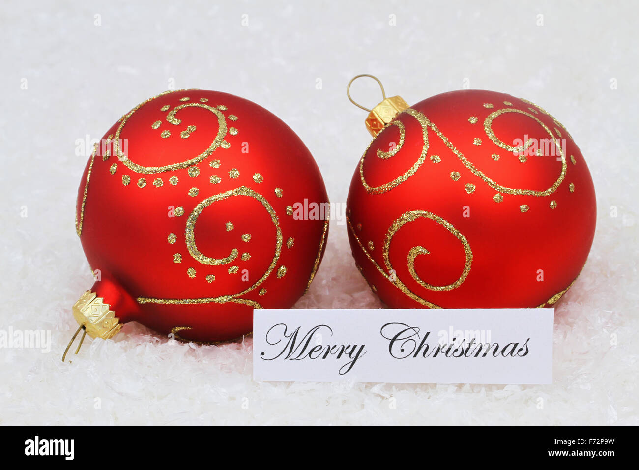 Merry Christmas card con due baubles rosso sulla superficie nevosa Foto Stock