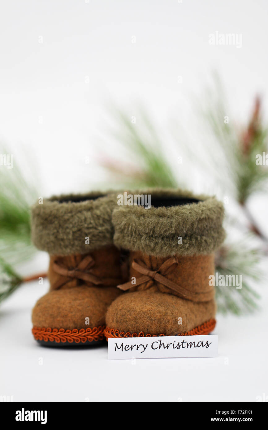 Buon Natale con scheda mini stivali di feltro e pino coperto con fiocchi di neve Foto Stock