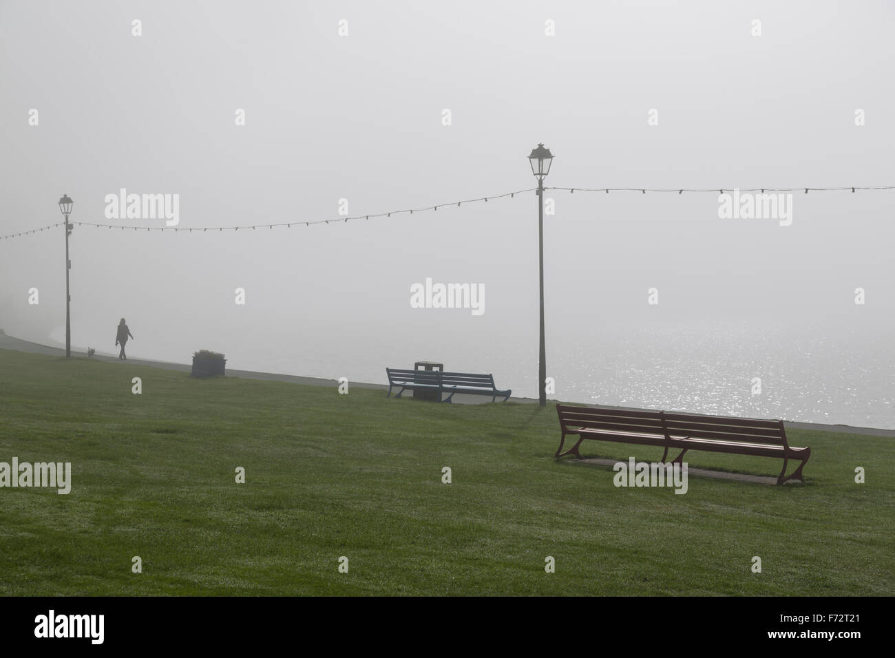 Donna che cammina con un cane in nebbia su una passeggiata sul mare, Regno Unito Foto Stock