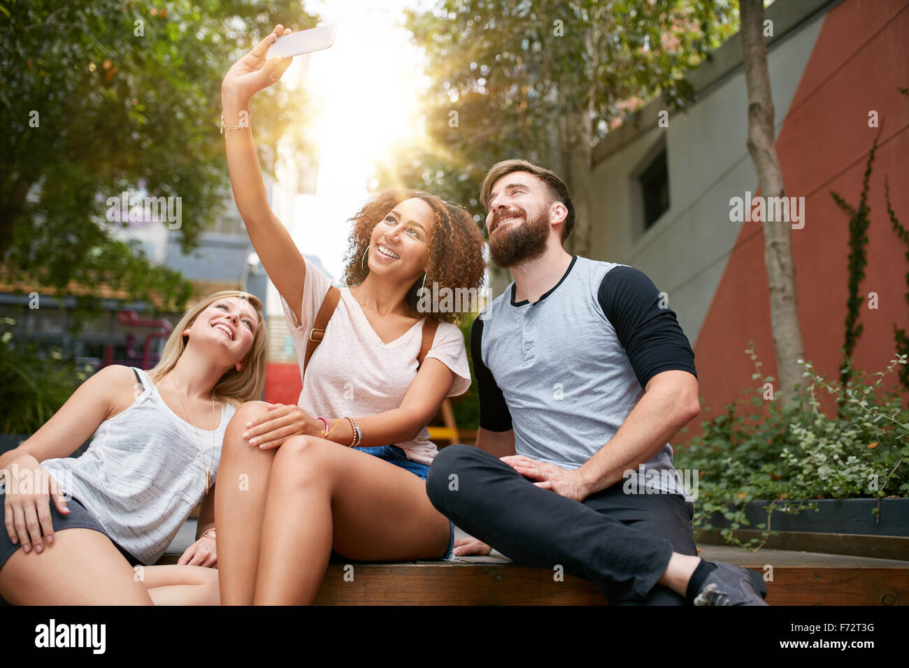 Gruppo di amici sorridenti tenendo selfie con smart phone. Multirazziale l uomo e la donna che si diverte all'aperto e prendendo pictu Foto Stock