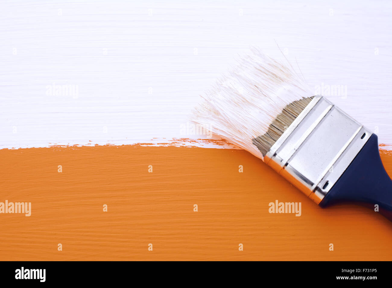 La verniciatura arancione superficie in legno con vernice bianca, pennello sporco si trova sulla parte superiore Foto Stock