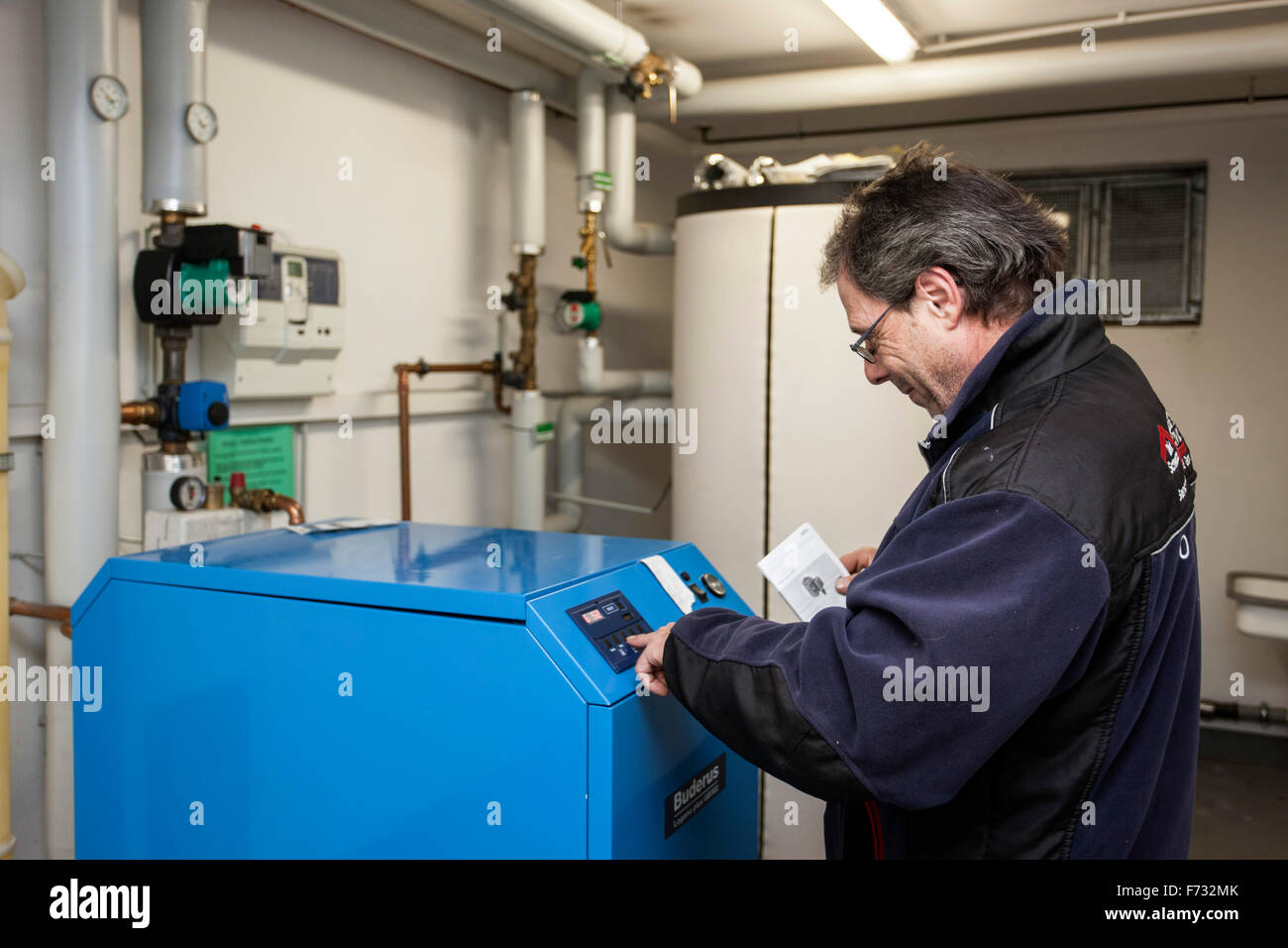 Custode controlla il sistema di riscaldamento nella sala caldaie Foto Stock