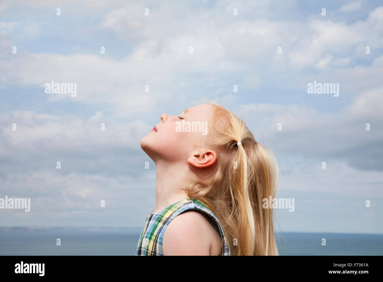 Una giovane ragazza alzando il suo volto al sole. Foto Stock