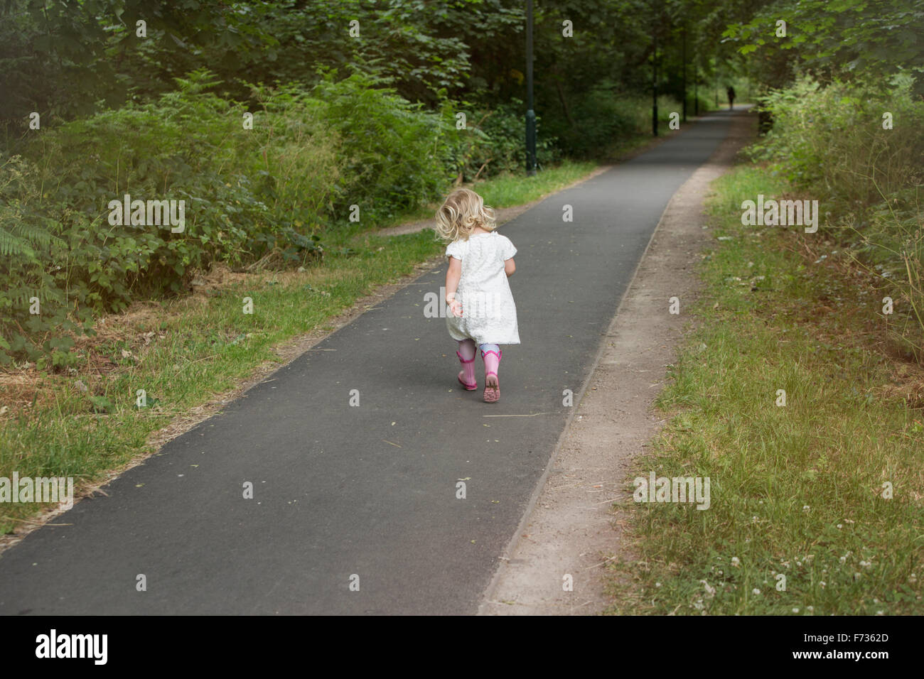 Giovane ragazza camminare lungo un percorso in un parco. Foto Stock