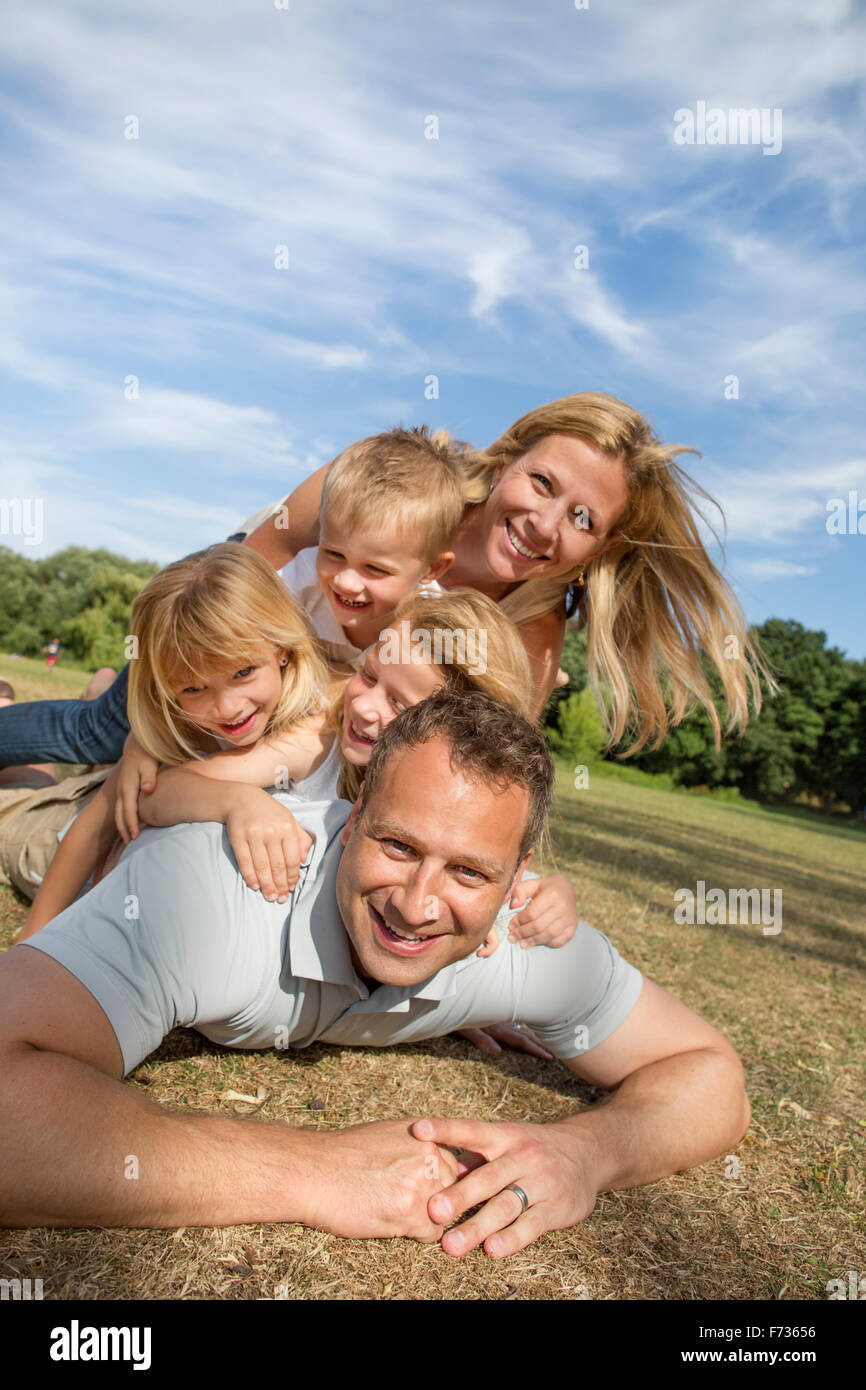 Famiglia con tre bambini che giocano in un parco. Foto Stock