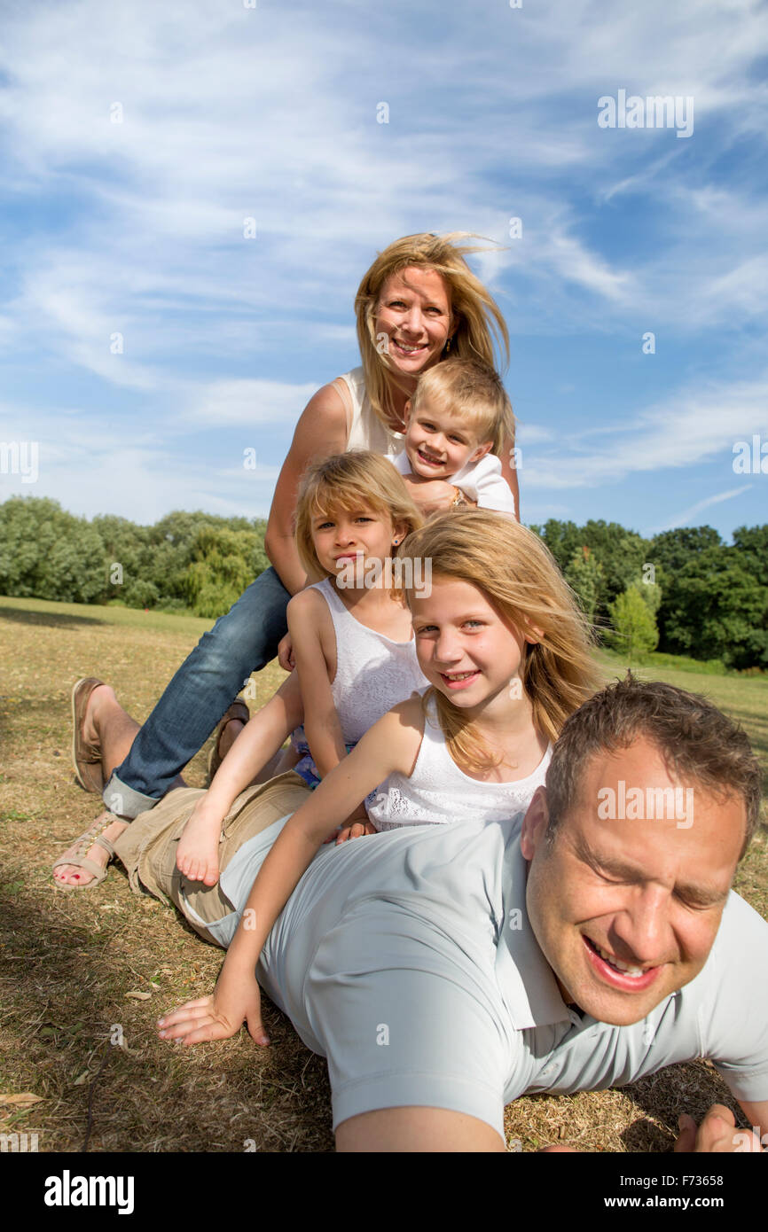 Famiglia con tre bambini che giocano in un parco. Foto Stock