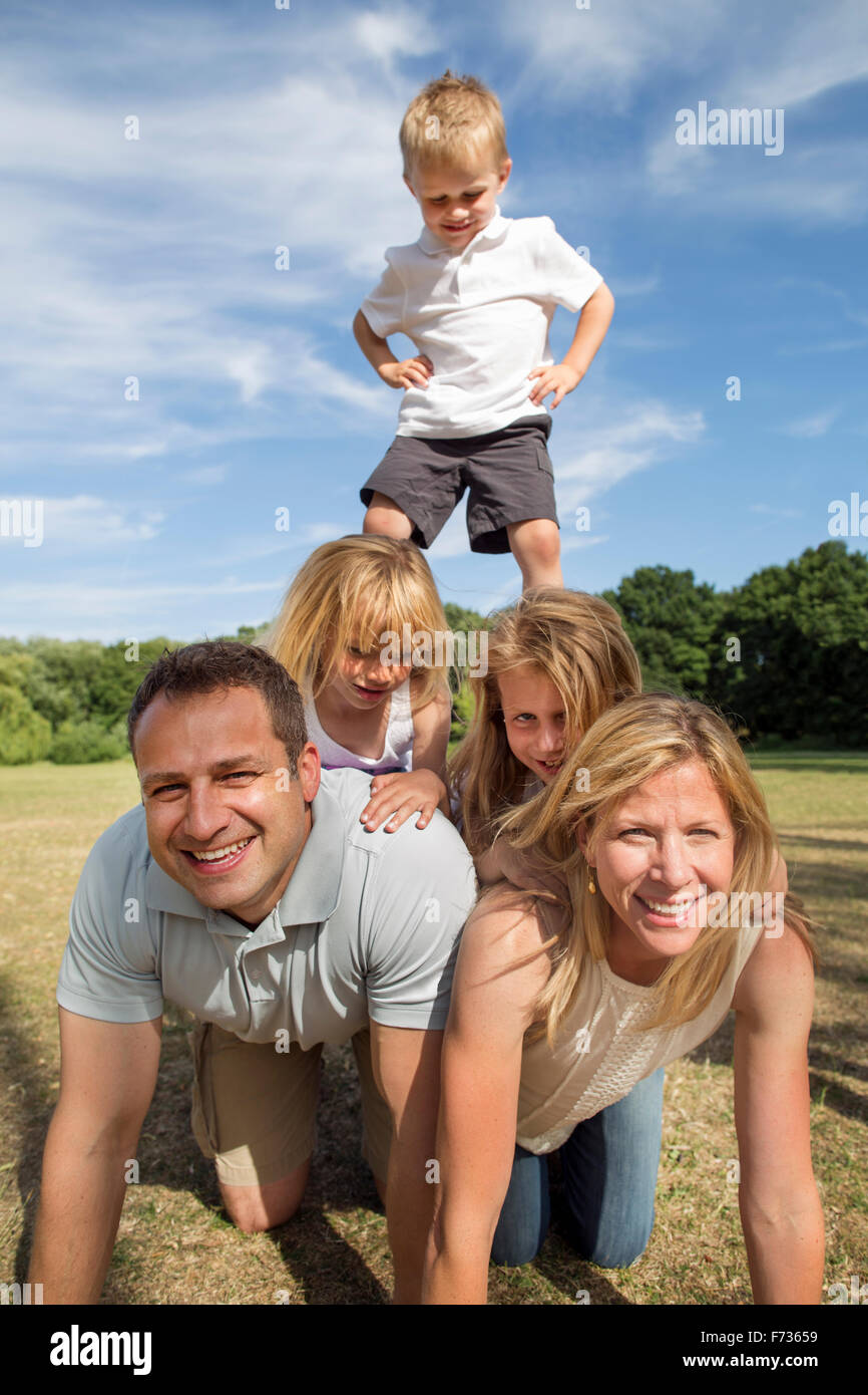 Famiglia con tre bambini che giocano in un parco. Foto Stock